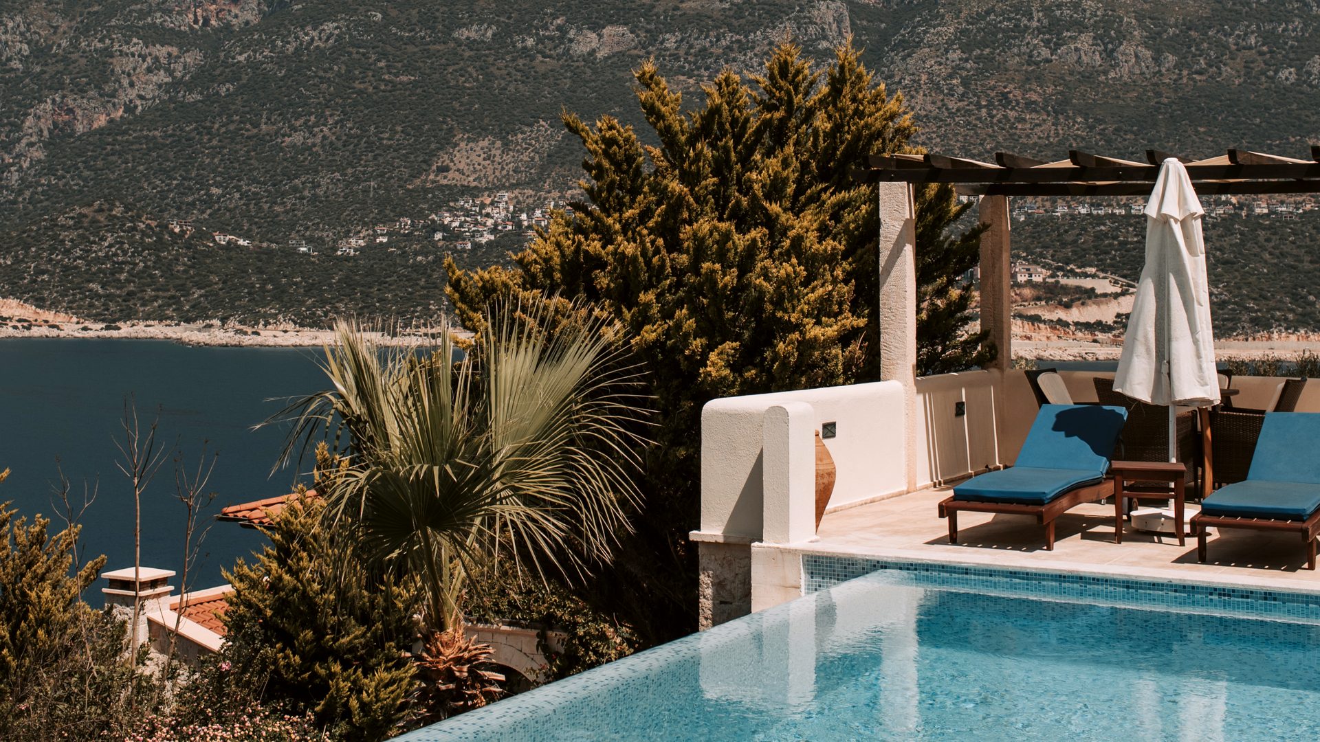 Villa terrace with an infinity pool and loungers looking over the sea